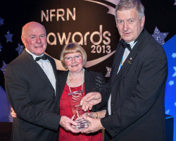 Joe Sweeney and his wife Margaret are pictured receiving the award from Mike Mitchelson, chairman of Newtrade Publishing, who sponsored the category